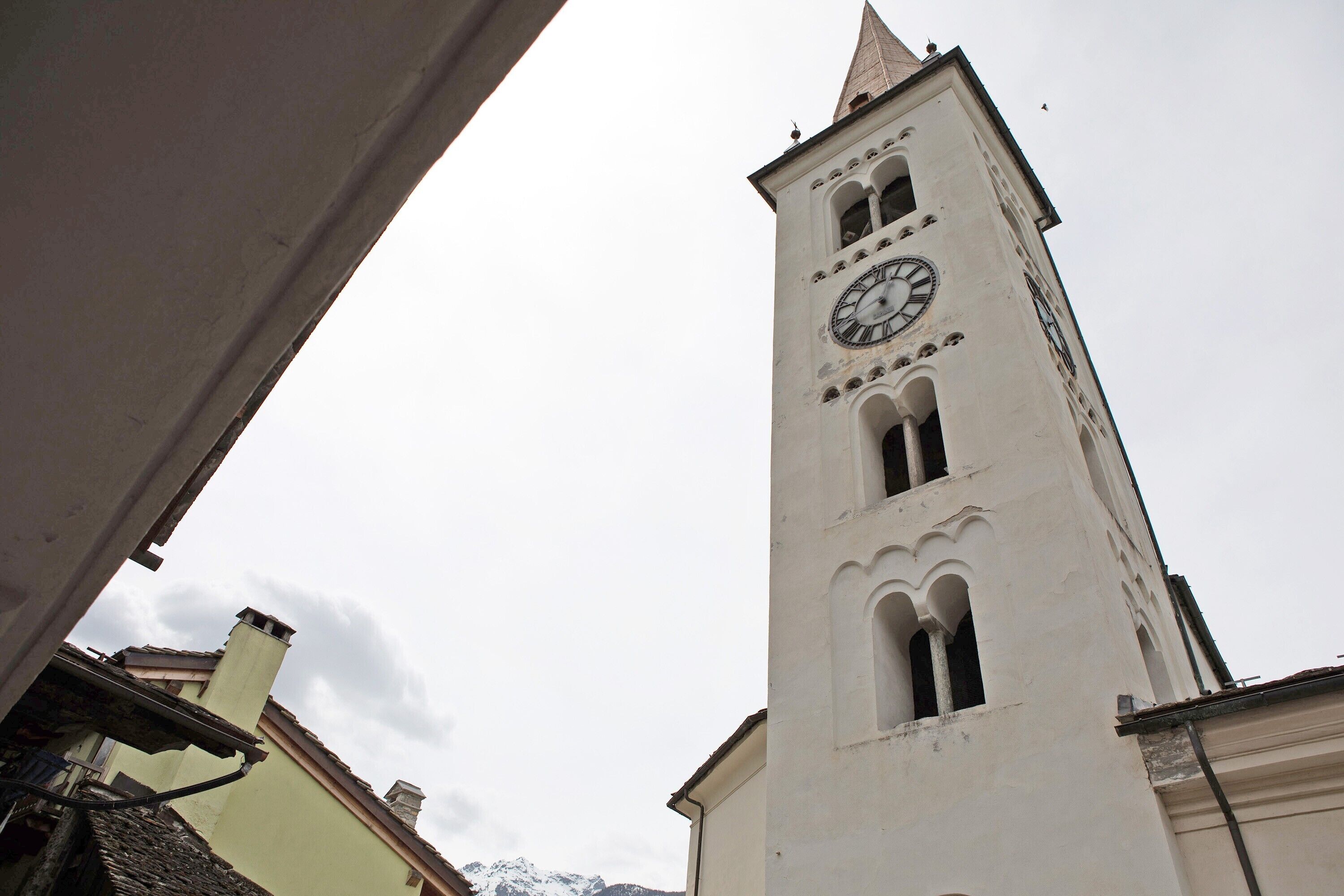Une haute tour blanche, dotée d’une horloge, de fenêtres en arc de cercle et d’un toit en forme de flèche.