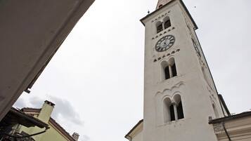 Une haute tour blanche, dotée d’une horloge, de fenêtres en arc de cercle et d’un toit en forme de flèche.