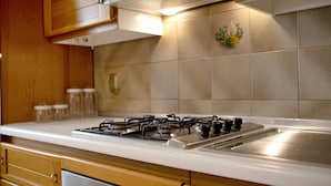 Une cuisine équipée d’une cuisinière à gaz, de meubles de rangement en bois et d’un dosseret carrelé.