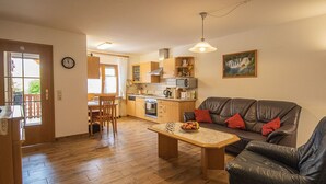 Een woonkamer met een bank, een salontafel en een eethoek met een stoel en tafel.