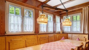 A wooden dining room with a large table, chairs, and hanging pendant lights. - Sägerhäusle Holiday Home – Rustic Black Forest Cabin at Feldberg (Feldberg)