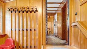 A wooden interior with a red chair, a wooden bench, and a wall-mounted coat rack. - Sägerhäusle Holiday Home – Rustic Black Forest Cabin at Feldberg (Feldberg)