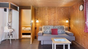A wooden-paneled room with a sofa, a small table, a chair, and a bed. - Holiday Apartment 'Mühle' – Cozy Getaway at Feldberg (Feldberg)