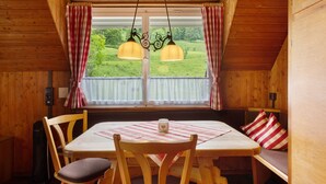 A wooden cabin with a dining table, chairs, a bench, and a window with curtains. - Holiday Apartment 'Mühle' – Cozy Getaway at Feldberg (Feldberg)