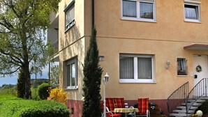 Ein Gebäude mit Balkon, Tisch und Stühlen sowie einer Treppe zum Eingang.