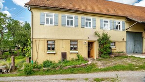 Kaksikerroksinen rakennus, jonka julkisivu on keltainen, siinä on useita ikkunoita, joissa on sälekaihtimet, ja siinä on ovi.