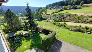 Un jardin avec un banc, une table de pique-nique et une haie.
