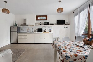 Eine kompakte Küche mit weißen Schränken, einer eingebauten Mikrowelle und einem kleinen Fenster über der Arbeitsfläche.