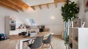 Een moderne keuken met houten balken, een dakraam en een eethoek met twee stoelen.
