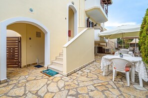 A stone-floored courtyard with a staircase, outdoor seating, and a covered area with umbrellas.