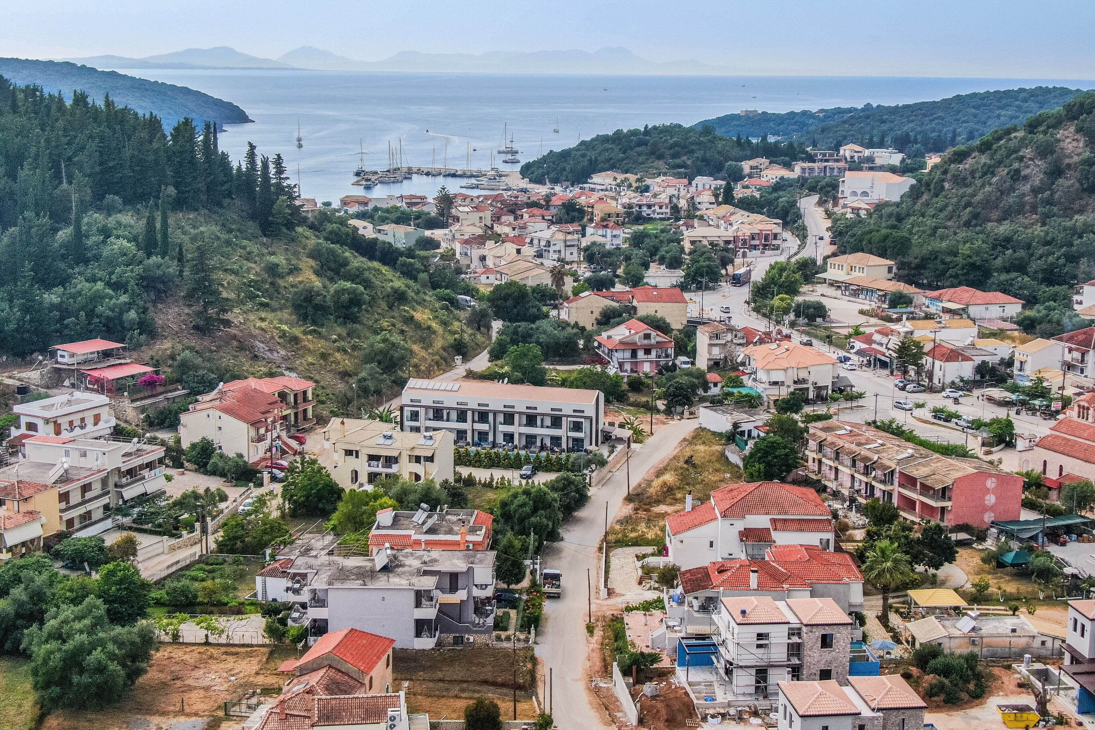 Un pueblo costero con edificios, una carretera y barcos en el agua.