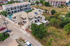 A multi-story residential building with a swimming pool, solar panels, and a gated driveway.