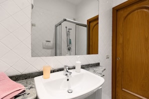 A bathroom with a white sink, a mirror, a shower, and a wooden door. - Room 'Camera 43' with Wi-Fi and Air Conditioning (Verona)