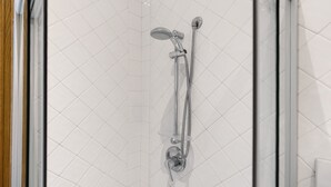 A shower with a handheld showerhead and a wall-mounted faucet.