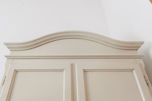 Een witte muur met decoratieve sierlijsten aan de bovenkant.