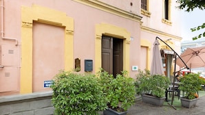 A building with a yellow facade, a closed door, and potted plants in front. - Room 'Camera 48' with Wi-Fi and Air Conditioning (Verona)