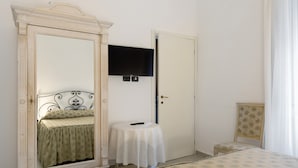 A bedroom with a bed, a bedside table, a mirror, a television, and a door. - Room 'Camera 48' with Wi-Fi and Air Conditioning (Verona)