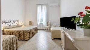 Habitación de hotel con dos camas, televisor, una silla y una planta en maceta.