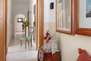 Ein Korridor mit einer Holzbank, einer Statue und einem gerahmten Bild an der Wand.