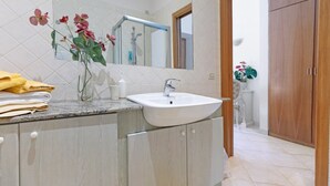 Un baño con lavamanos, espejo y puerta de madera.