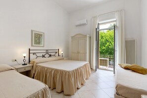 Un dormitorio con dos camas, una mesita de noche, un aparador y una ventana con vistas al verdor.