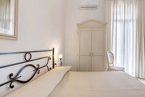 A bedroom with a bed, a wardrobe, a mirror, and a wall-mounted air conditioner.