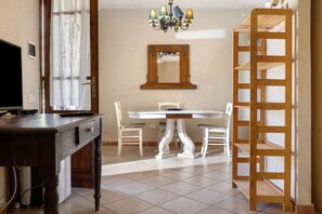 A dining area with a white table, chairs, a wooden chair with a backrest, a chandelier, and a wooden ladder.