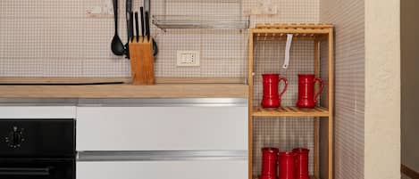 Een keuken met een houten aanrecht, een witte vaatwasser en een rode plankenwand voor mokken.