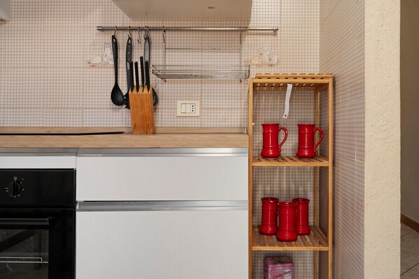 A kitchen with a wooden countertop, a white dishwasher, and a red mug shelf.