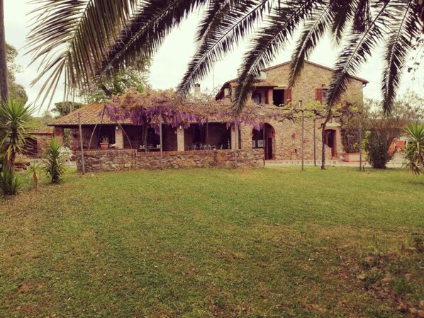 A stone house with a covered patio and a lawn.