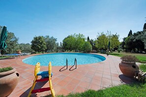A swimming pool with a tiled deck, a children's play structure, and potted plants. - Apartment 'Cabernet' with Shared Pool, Private Terrace and Shared Garden (Suvereto)