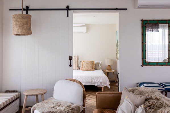 Una habitación con cama, una silla, una mesita y una lámpara colgante.