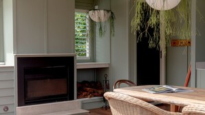 A cozy living room with a fireplace, a wicker table, and hanging plants. - Sunbird Suite by Stay Noosa (Noosa Heads)