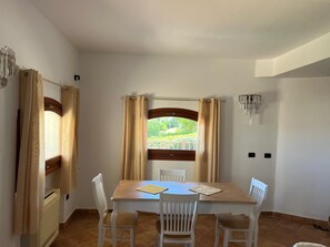 Un comedor con una mesa, sillas y vistas por una ventana.