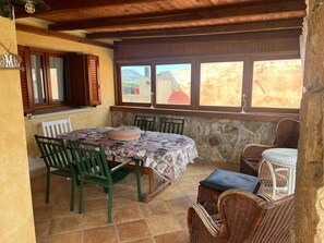 A dining area with a table, chairs, and a view through large windows. - Villa 'Oriana' with Private Terrace, Garden, and Air Conditioning (Porto San Paolo)