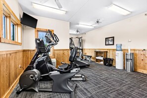 A gym with exercise equipment, a water dispenser, and a ceiling fan.