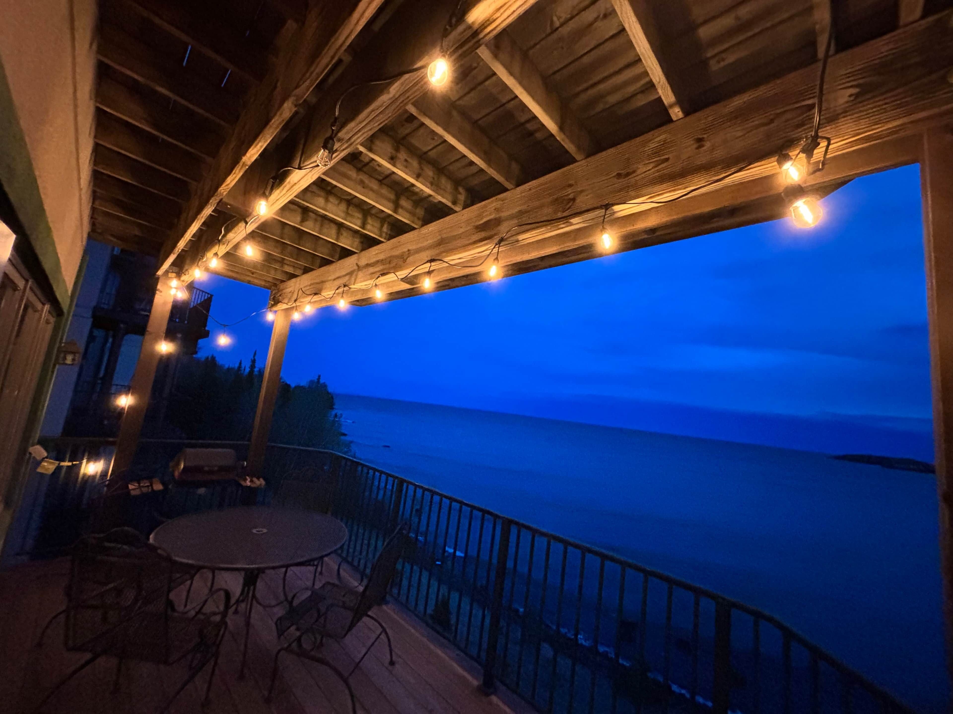 An outdoor deck with string lights, a round table, and chairs.