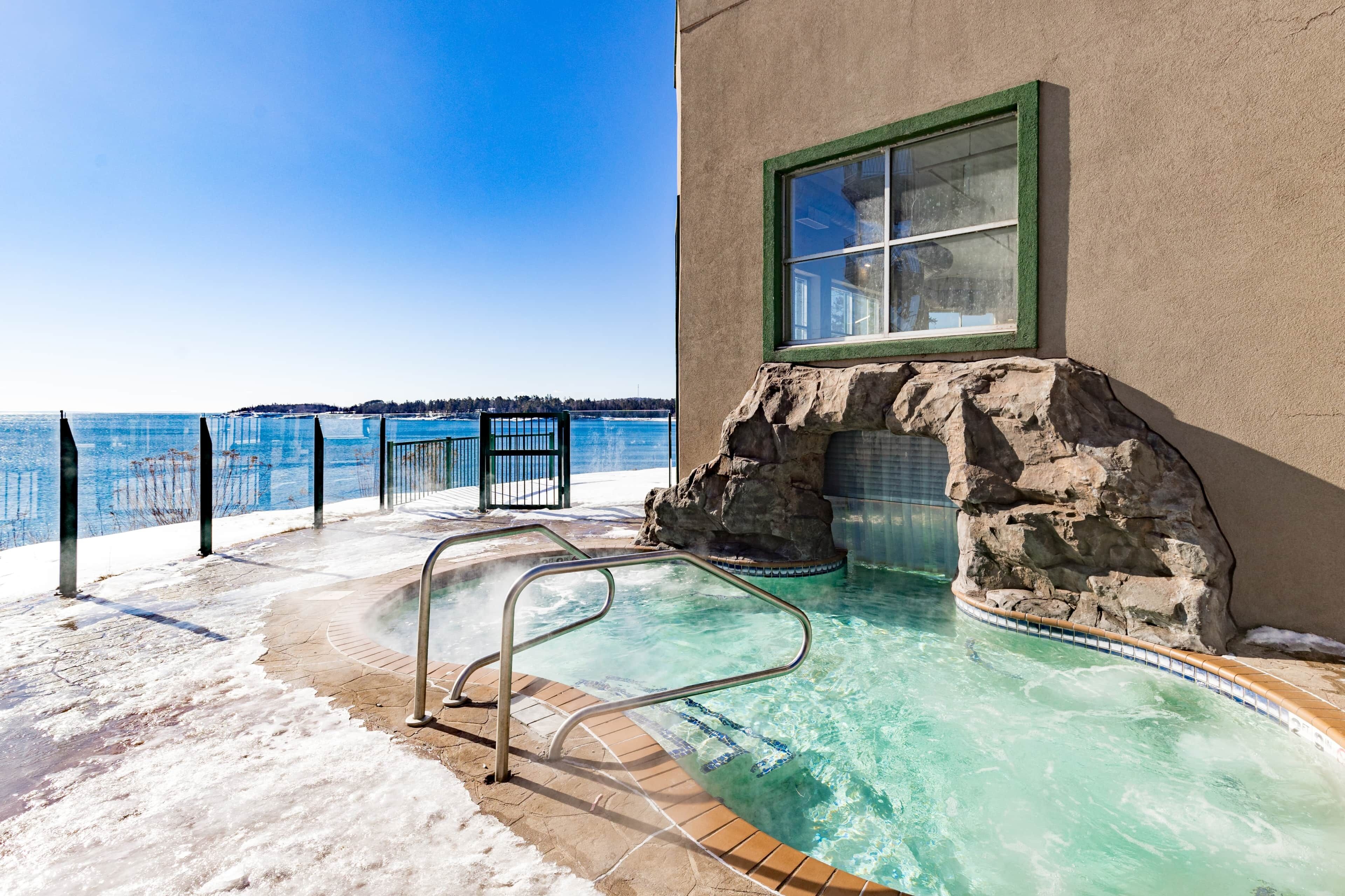 Ein Außenpool mit Glasbarriere, einer Metallleiter und Blick auf das Meer.