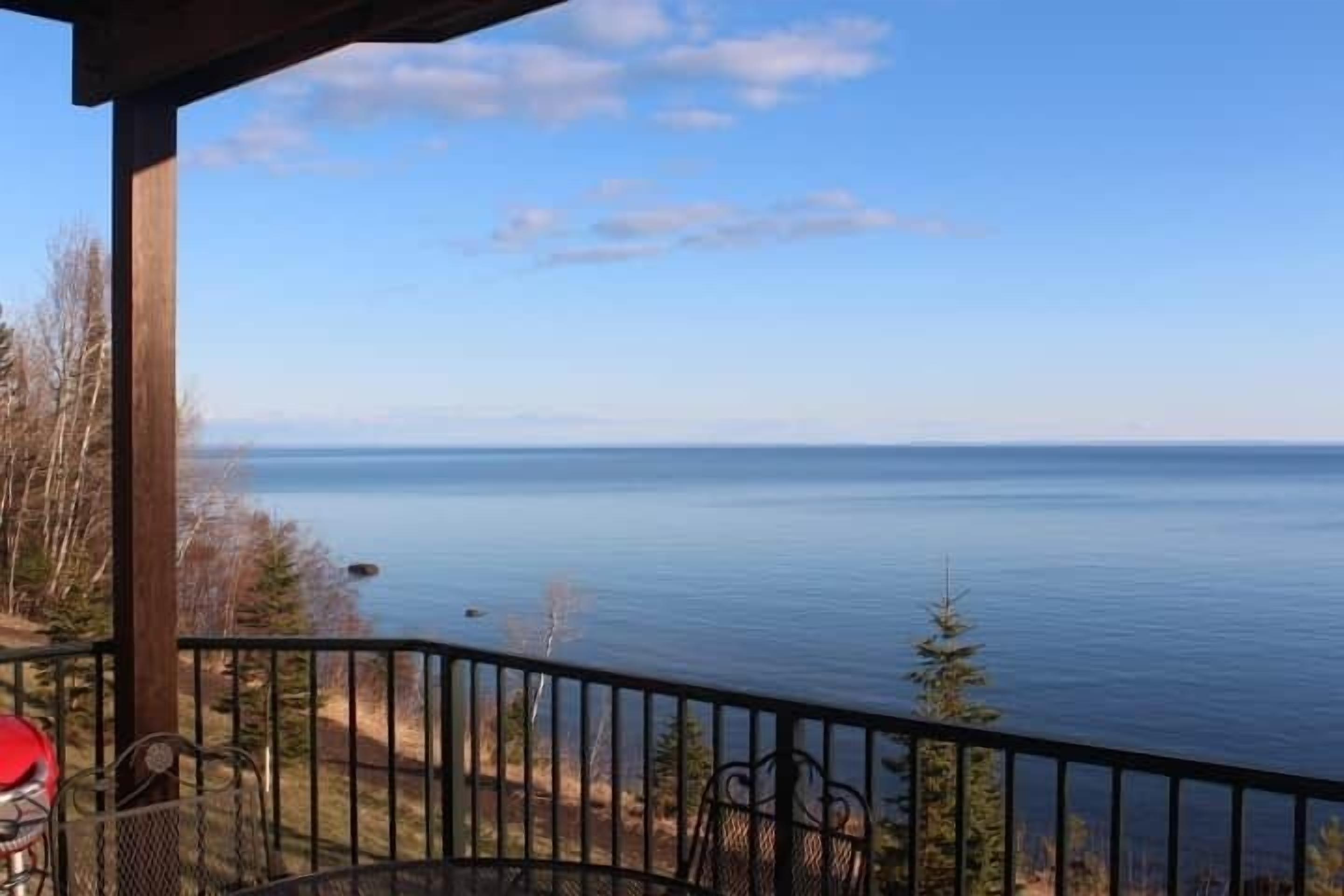 A balcony with a view of a calm body of water and distant land.