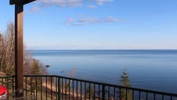 A balcony with a view of a calm body of water and distant land.