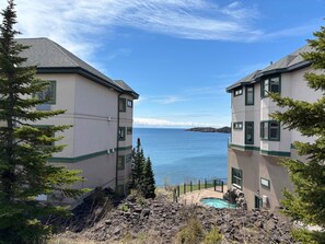 A coastal property with two buildings, a swimming pool, and a view of the sea. - Amazing Lake Views | 1BR w/ King Suite | Pools (Two Harbors)