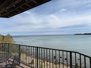 A balcony with a view of a calm body of water, a distant shoreline, and a cloudy sky. - Amazing Lake Views | 1BR w/ King Suite | Pools (Two Harbors)