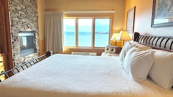 Hotellihuone, jossa on suuri sänky, kiviseinä, merinäköalalla varustettu ikkuna ja takka.