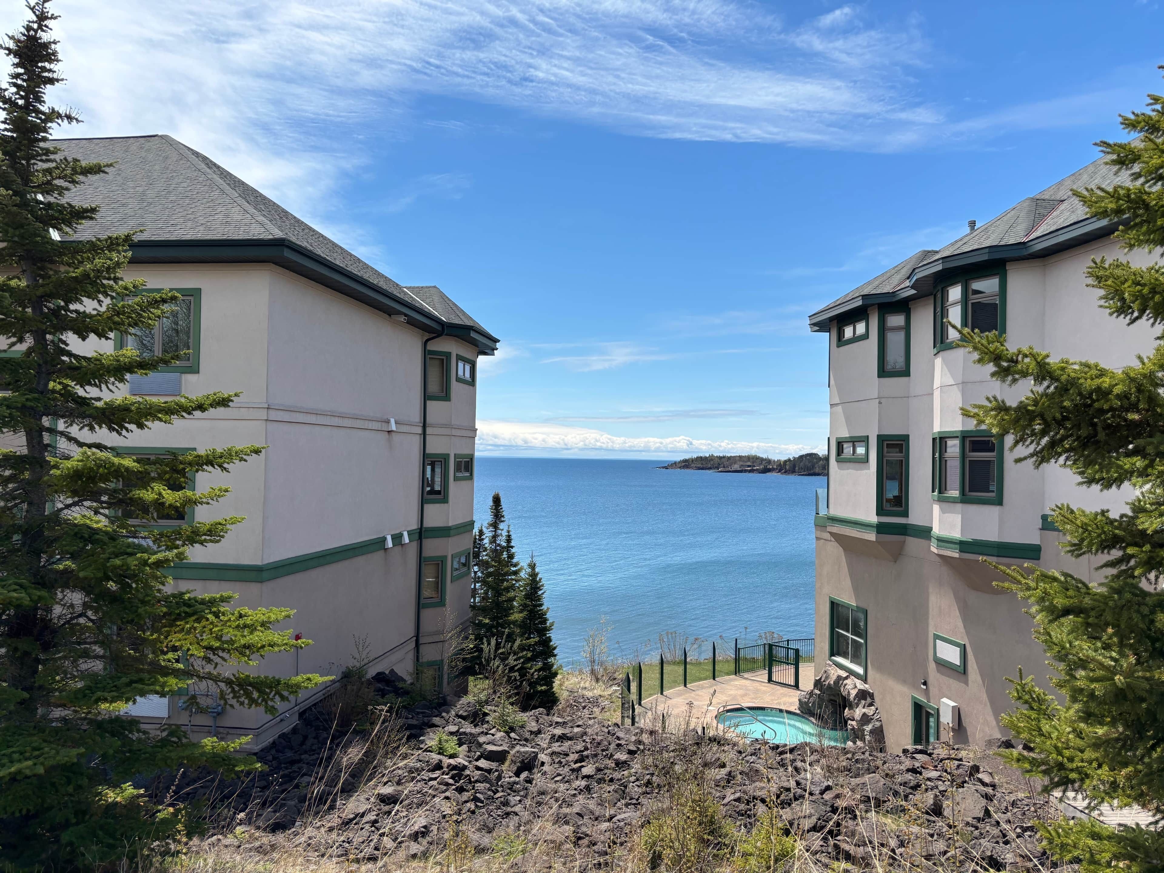 A coastal property with two buildings, a swimming pool, and a view of the sea.