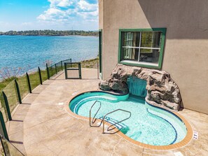 A swimming pool with a view of a lake, a stone waterfall feature, and a patio area with a glass railing. - Amazing Lake Views, Studio, 2 Queen Beds & Pools (Two Harbors)