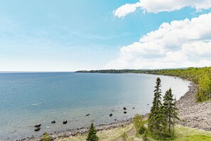 A coastal landscape with a clear view of the water, a rocky shoreline, and a forested area. - Amazing Lake Views, Studio, 2 Queen Beds & Pools (Two Harbors)