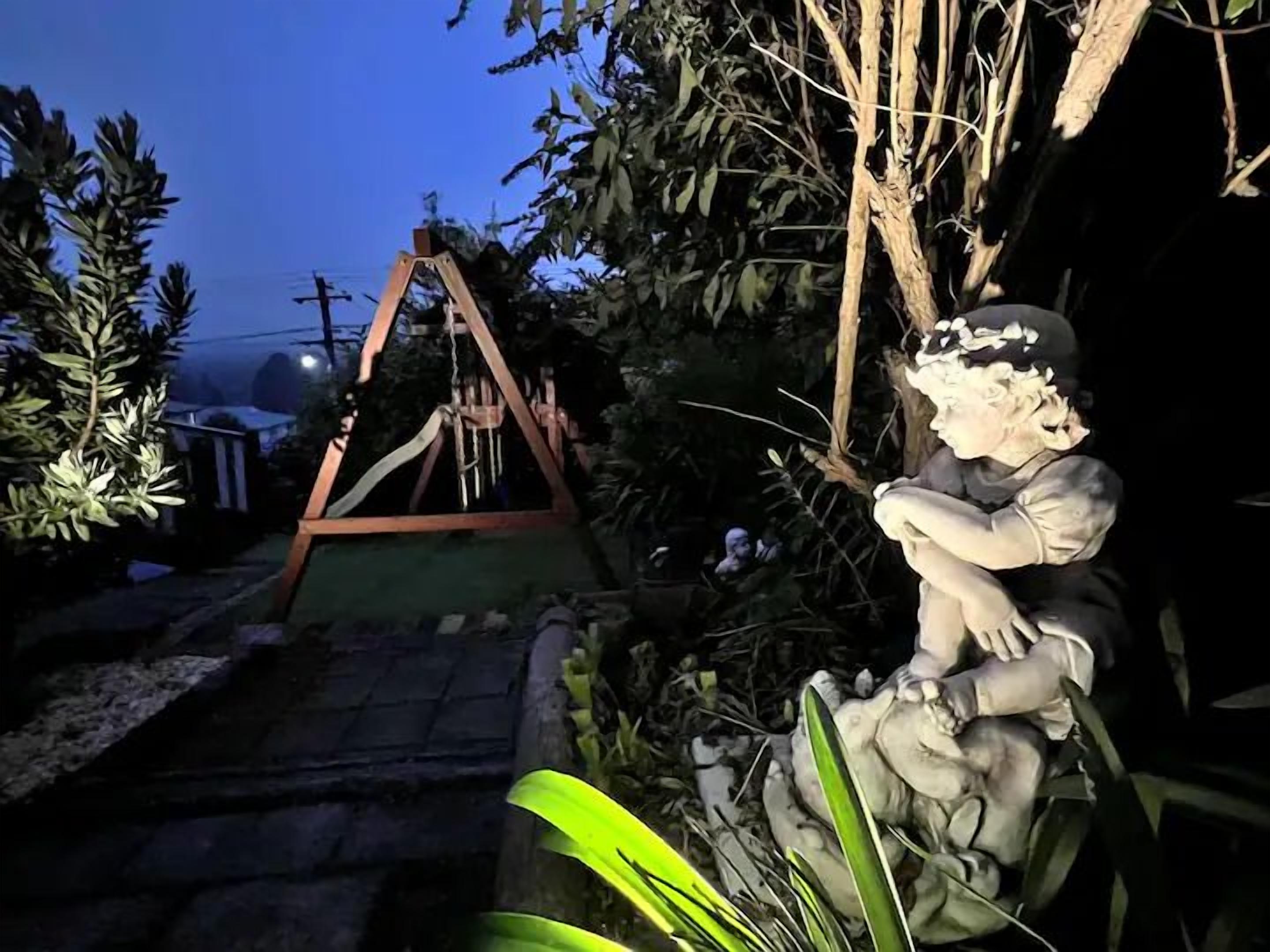 A garden with a swing set and a statue.