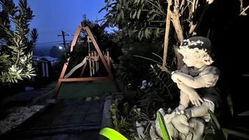A garden with a swing set and a statue.