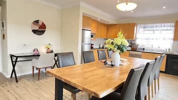 A modern kitchen with wooden cabinets, a central island, and a dining area with a wooden table and chairs.