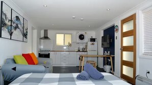 Une chambre d’hôtel de taille réduite comprenant un lit, une kitchenette, une petite table à manger et une salle de bain.